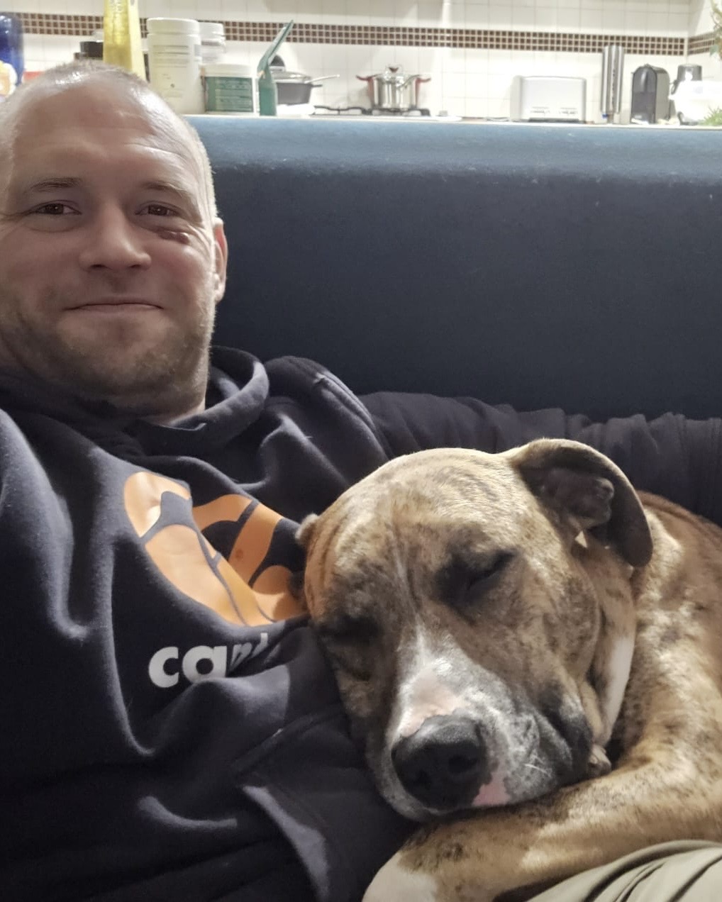 Large dog foster carer Greg with his foster dog sleeping on his lap